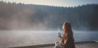 Mushrooms For Relaxation: Supplements That Can Help Young woman relaxing near lake beach and drinking mushroom drink