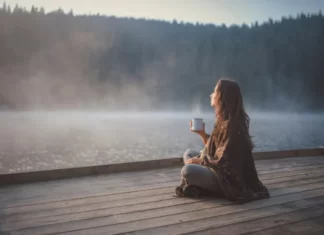 Young woman relaxing near lake beach and drinking mushroom drink