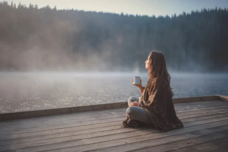 Young woman relaxing near lake beach and drinking mushroom drink