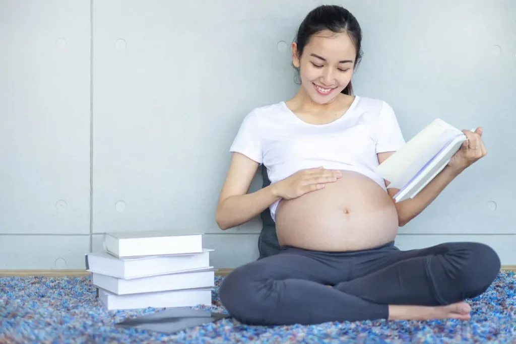 A pregnant lady reading the books. 